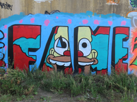850609 Afbeelding van graffiti met de tekst 'FAME', met daarin een clownsgezicht verwerkt, op een muur langs de ...